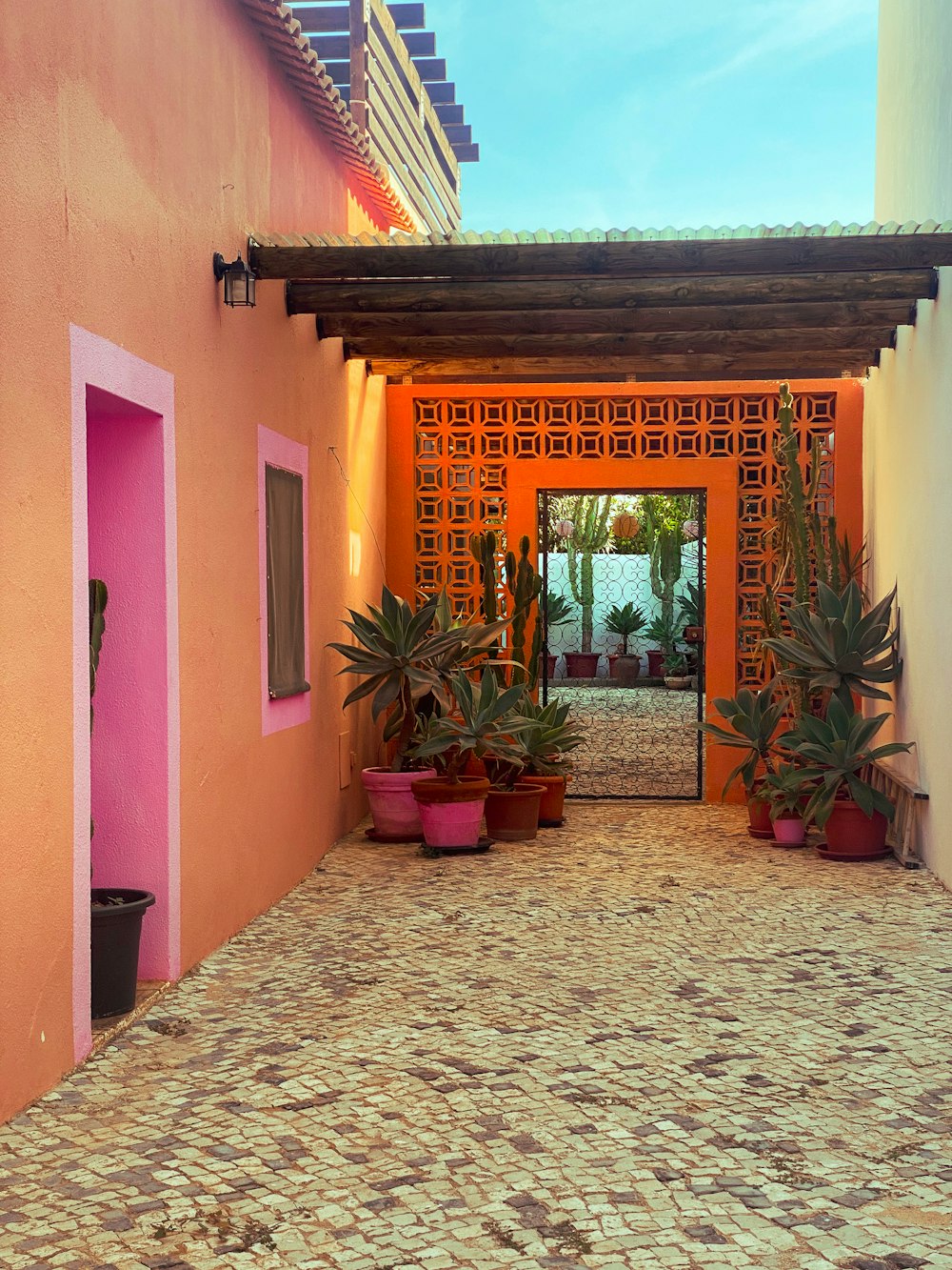 a pink and orange building with potted plants