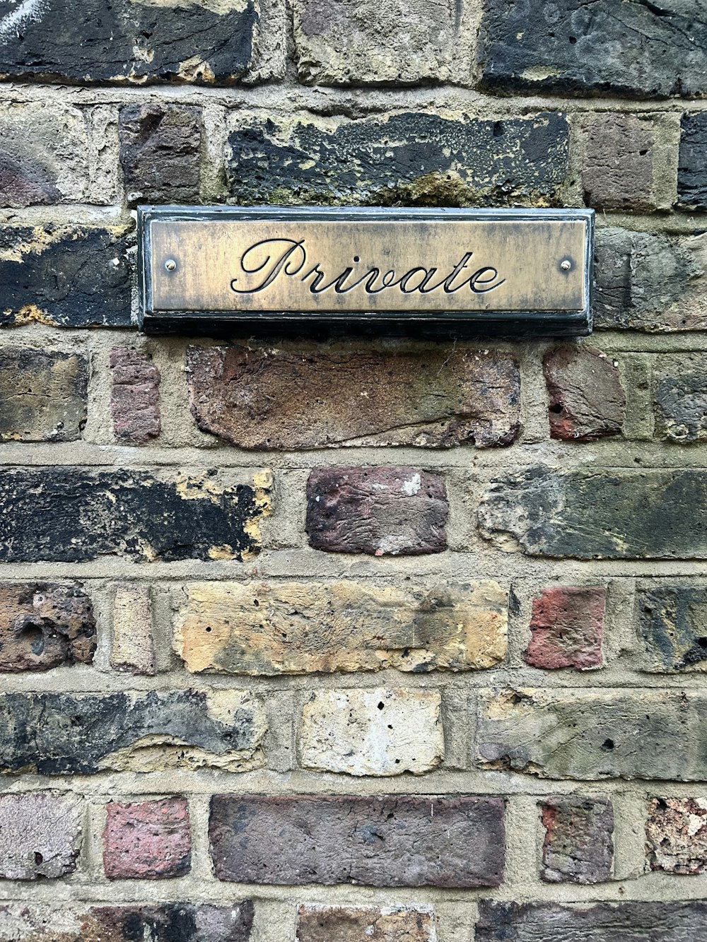 a brick wall with a plaque that reads private