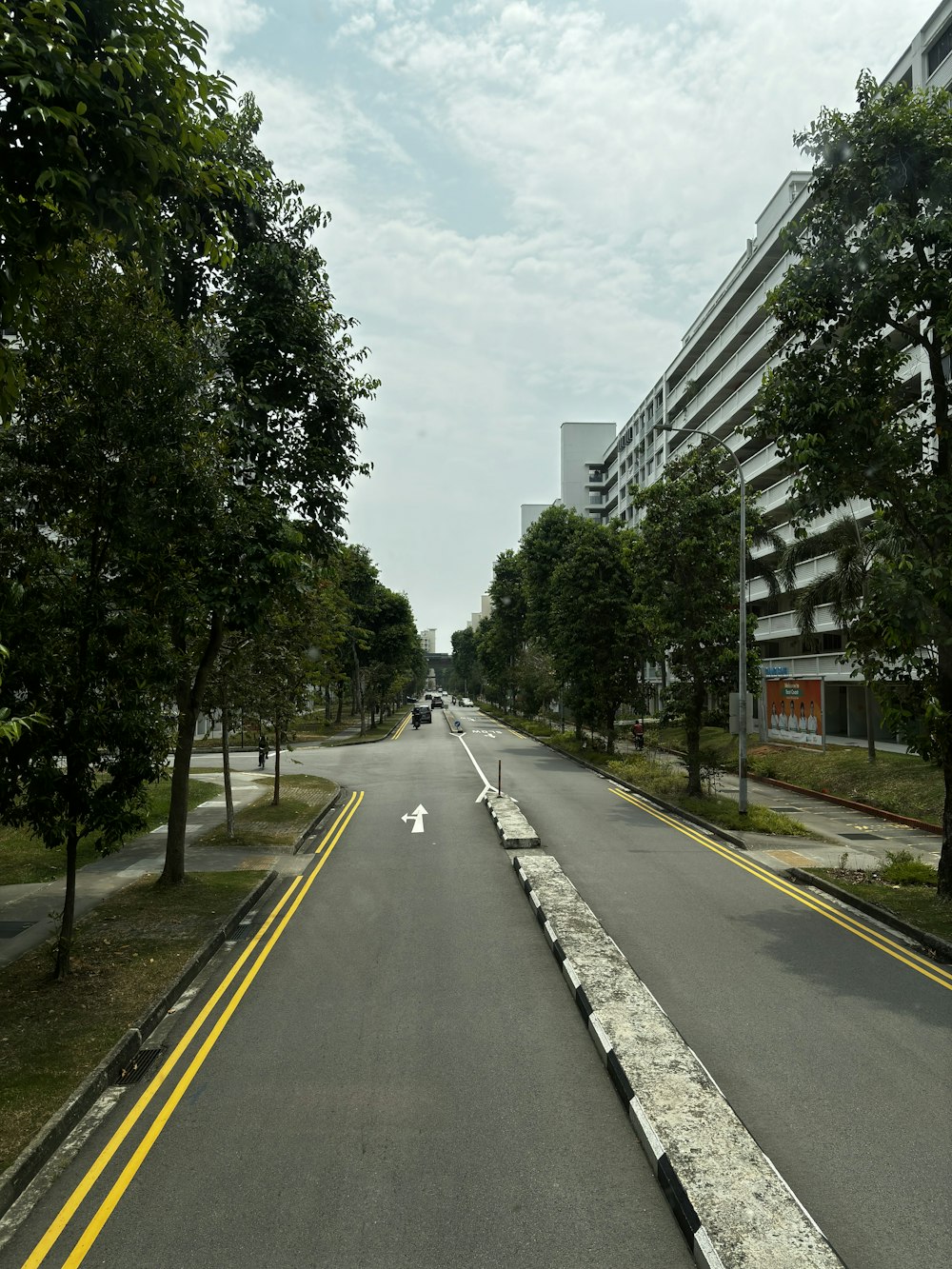a long empty street with trees and buildings in the background