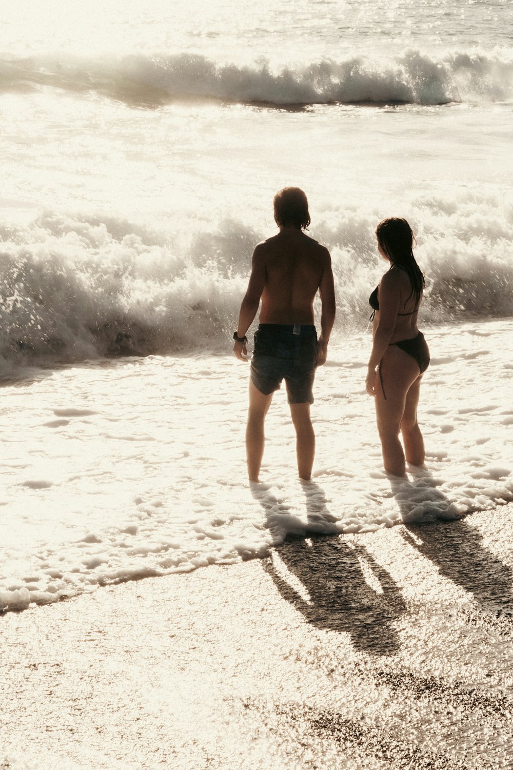 un uomo e una donna in piedi su una spiaggia vicino all'oceano