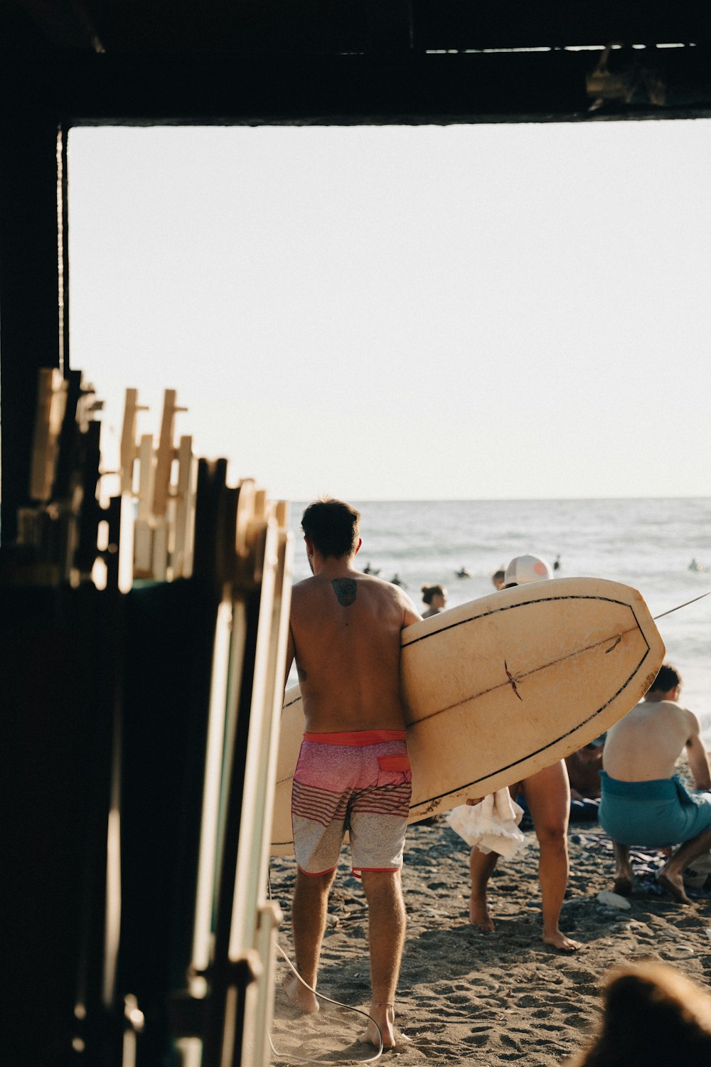 Ein Mann hält ein Surfbrett auf einem Sandstrand