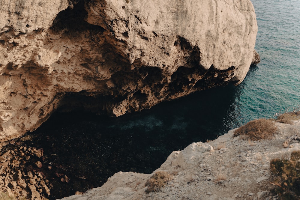 a rocky cliff with a body of water below