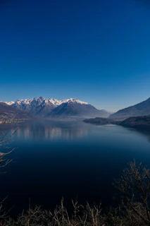 The serene waters of Mansarovar lake reflecting the towering Kailash mountain under a clear blue sky
