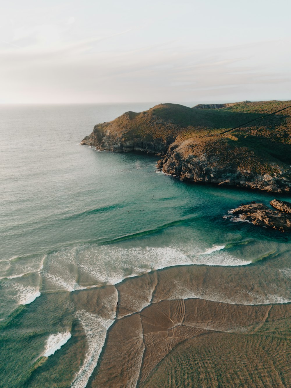 an aerial view of a beach with waves crashing on the shore