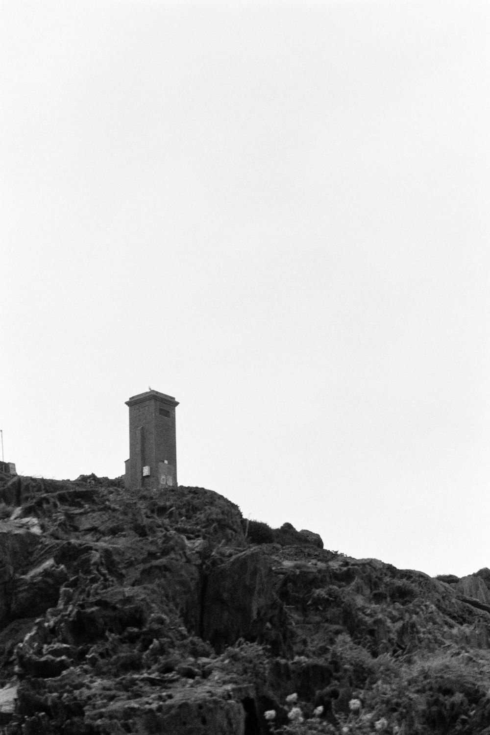 a black and white photo of a tower on a hill