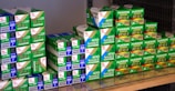 A collection of Fujifilm photographic film boxes, neatly stacked with labels such as Sensia II, Provia, and Fujicolor Superia Reala. The boxes are primarily green and white with some blue and red accents, arranged on a reflective surface.