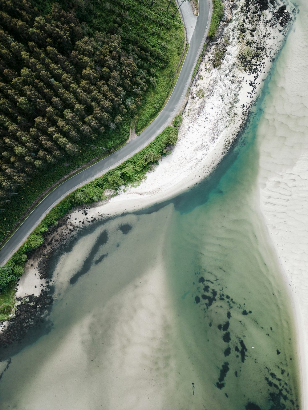 an aerial view of a winding road near a beach