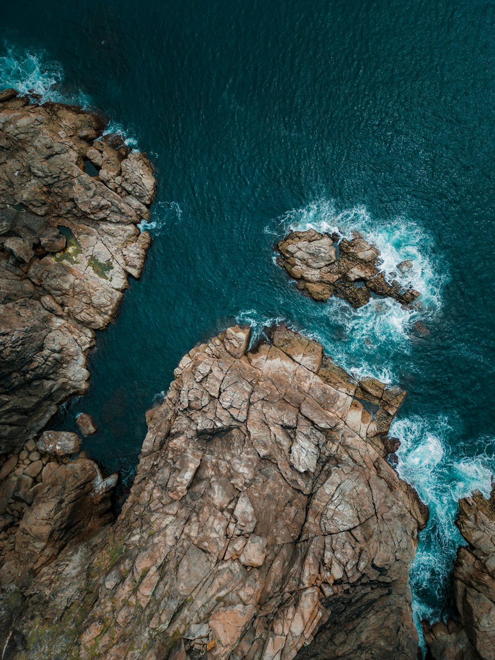 an aerial view of a rocky coastline with blue water