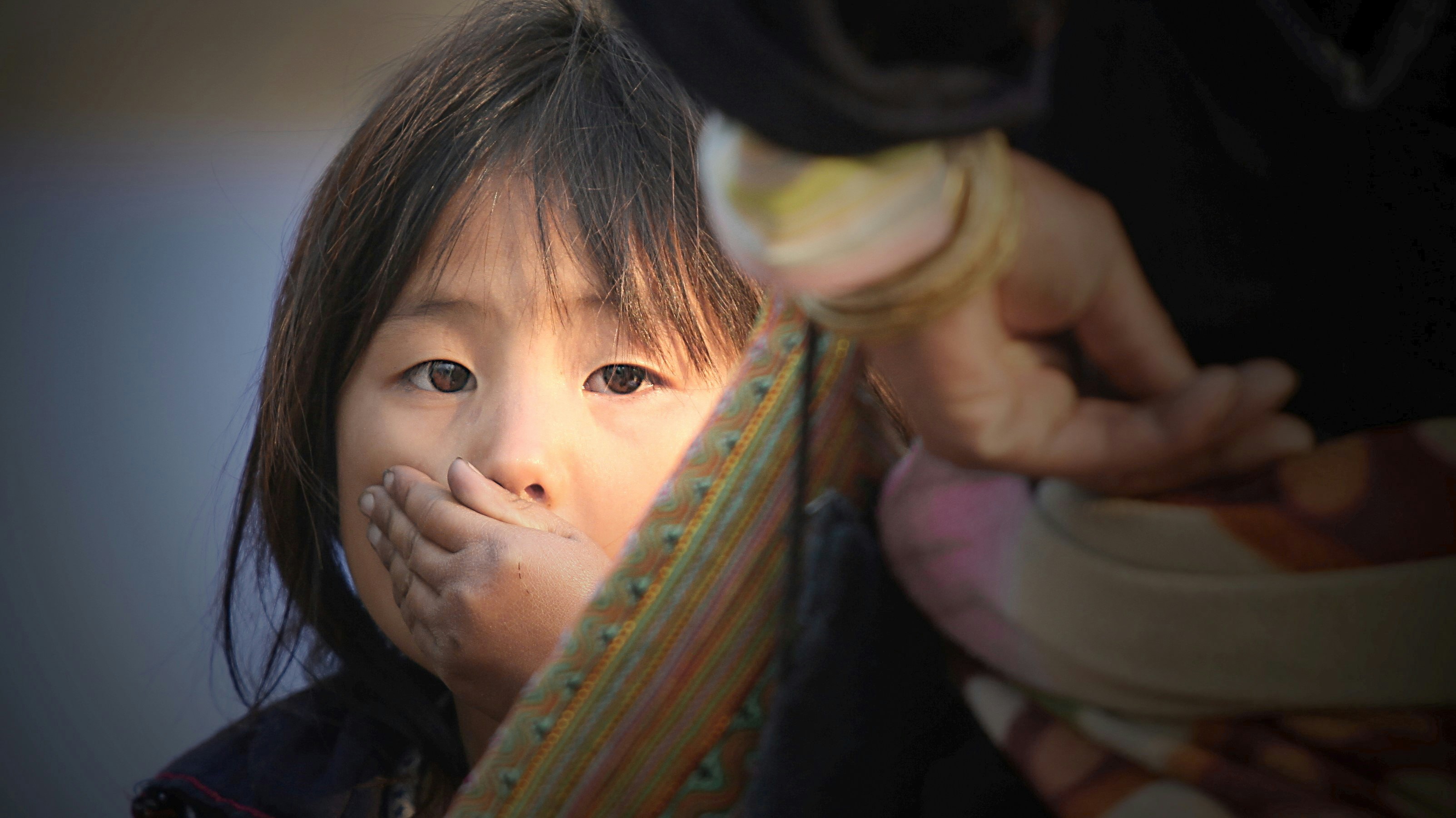ein kleines Mädchen mit den Händen vor dem Gesicht