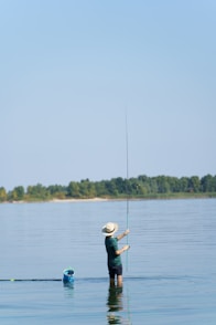 a man standing in the water holding a fishing pole