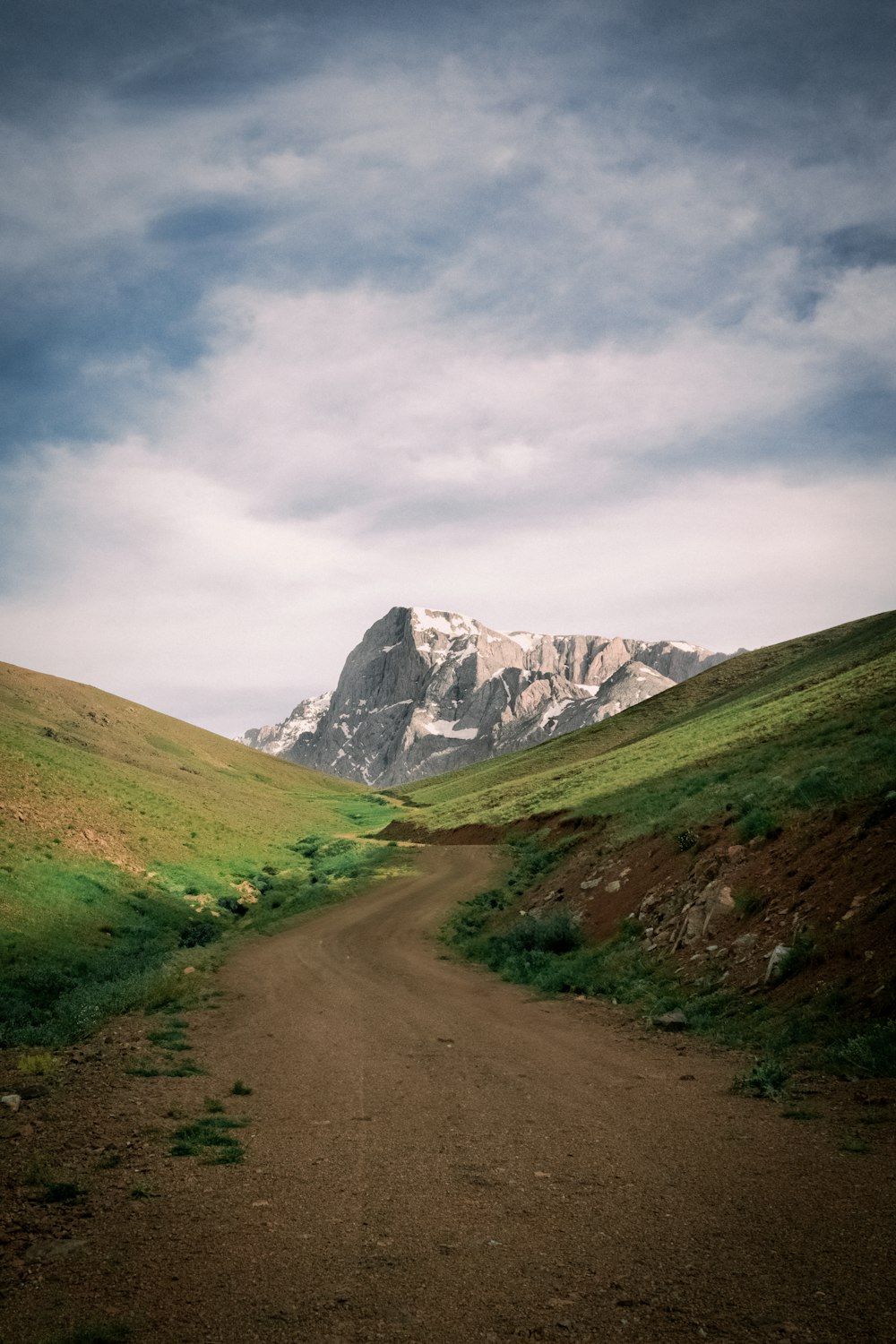 a dirt road with a mountain in the background