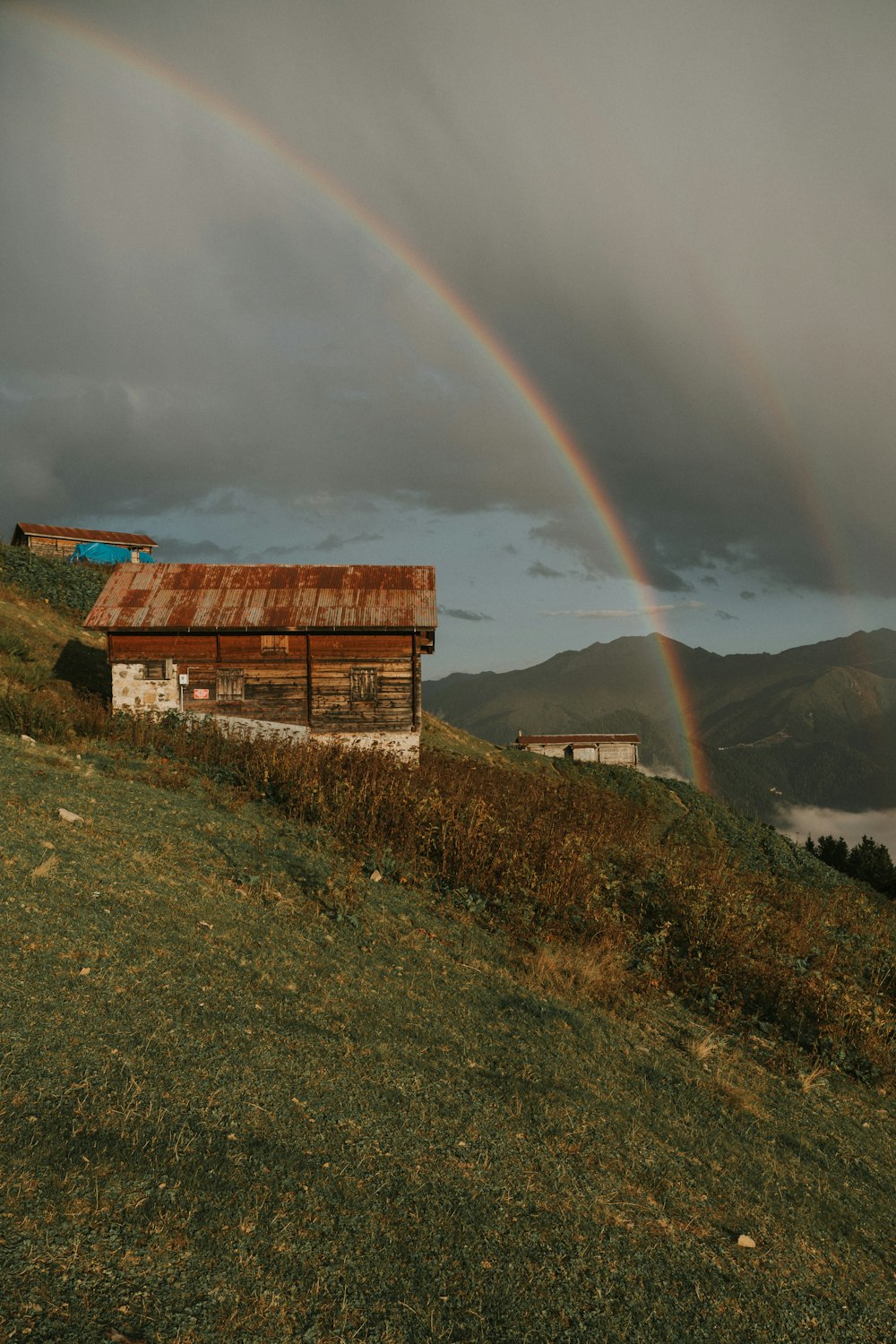 una casa su una collina con un arcobaleno sullo sfondo