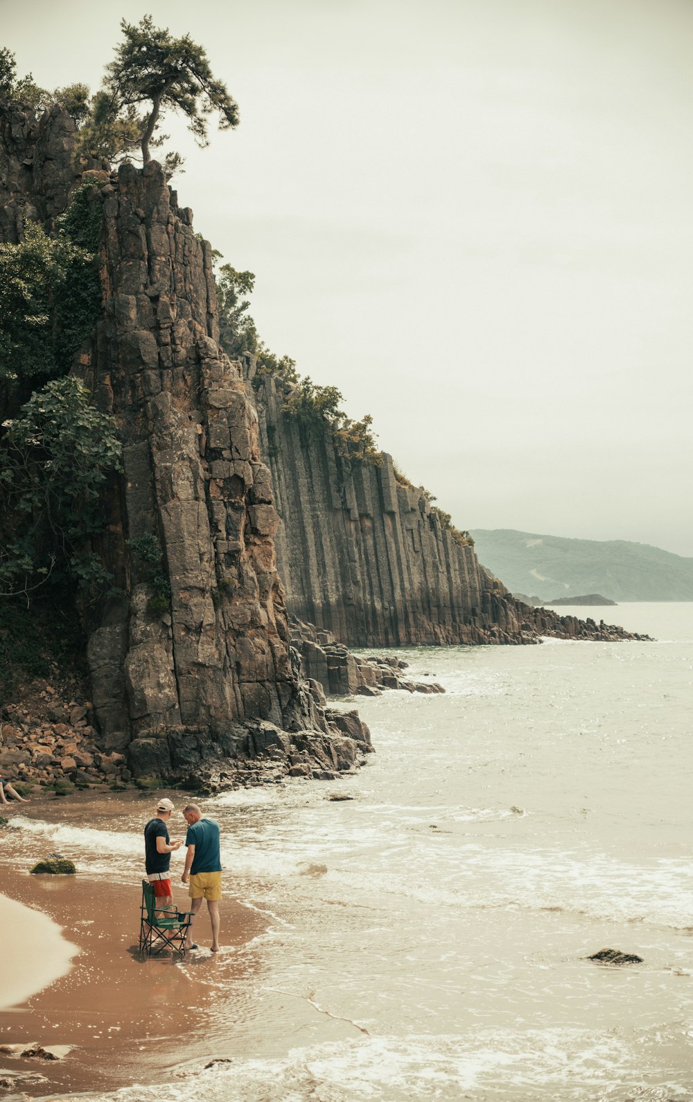 un groupe de personnes debout au sommet d’une plage de sable