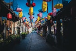 Narrow cobblestone street lined with vibrant houses and hanging lanterns.