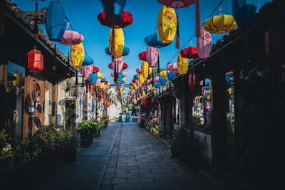 Narrow cobblestone street lined with vibrant houses and hanging lanterns.