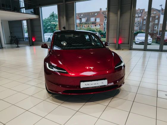 A vibrant group of happy Tesla owners holding their stock certificates with a backdrop of a Tesla showroom.