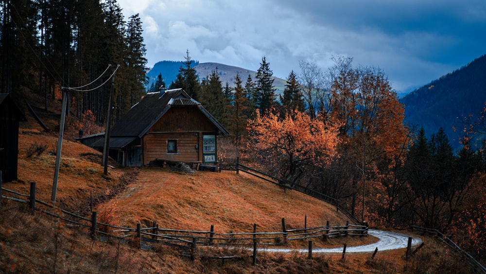 a small wooden house on a hill with a forest in the background