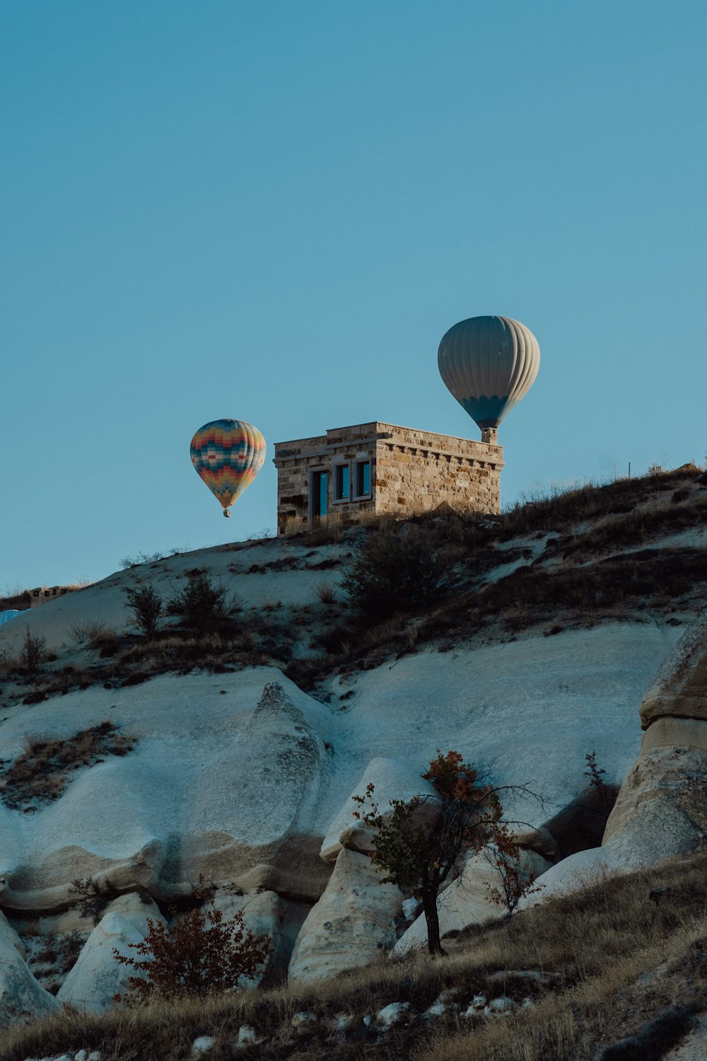 two hot air balloons flying over a rocky hillside