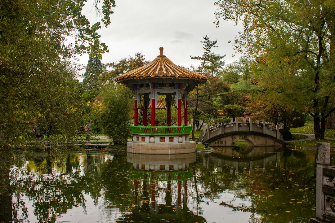 a gazebo in the middle of a pond with a bridge in the background,
