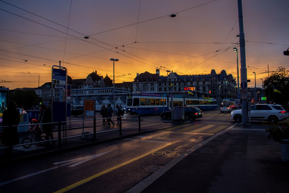 a group of people walking across a street at sunset