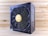 A black and gold power supply unit featuring a prominent cooling fan with a circular grille and a gold emblem in the center. The surrounding wood-textured surface accentuates the industrial design of the unit. The brand name is prominently displayed on the side and on the fan grille.