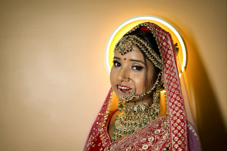 A bride glowing with radiant makeup and intricate hair styling, adorned in traditional Indian bridal attire.
