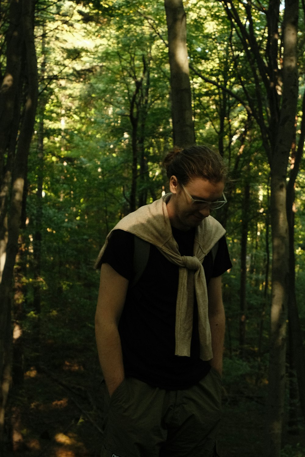 a man standing in the woods with a scarf around his neck