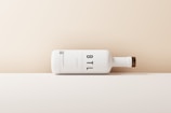 A minimalist, horizontally positioned white matte bottle with a wooden cap design. Large black letters 'BTL' are prominently displayed on the side. The background features a gradient of beige to cream, creating a clean, modern aesthetic.
