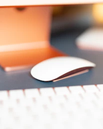 Close-up of a modern wireless mouse resting on a minimalist desk with tech gadgets around.