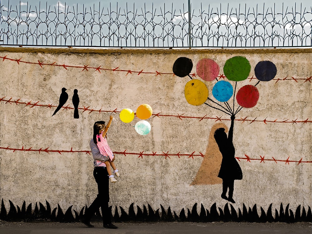 a woman standing in front of a wall with balloons