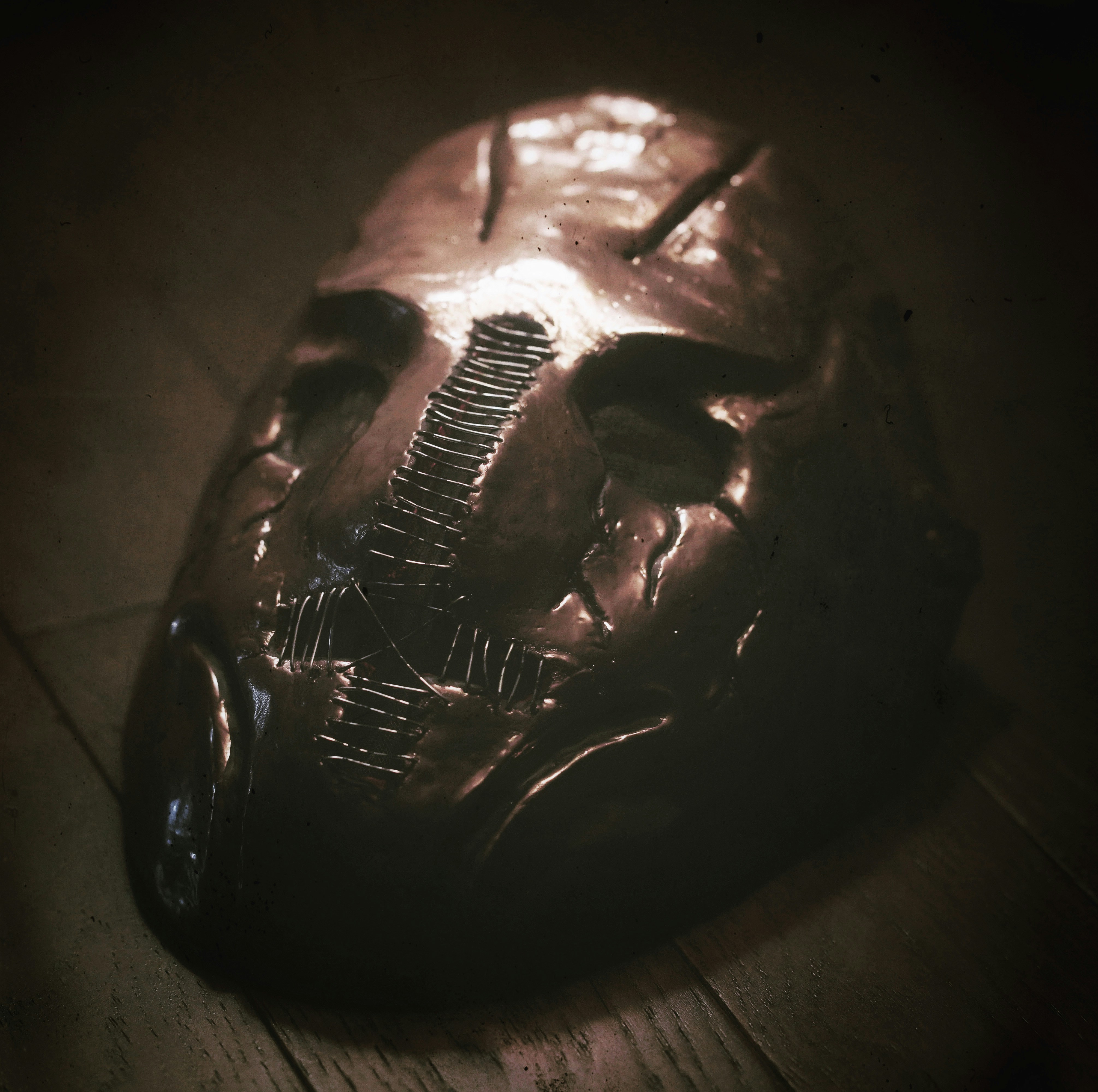 a metal mask sitting on top of a wooden floor