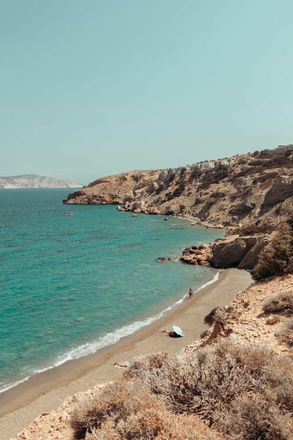 a beach with a body of water next to a cliff