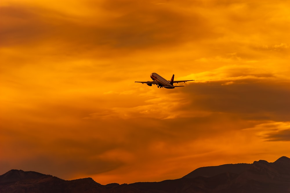 an airplane is flying in the sky at sunset