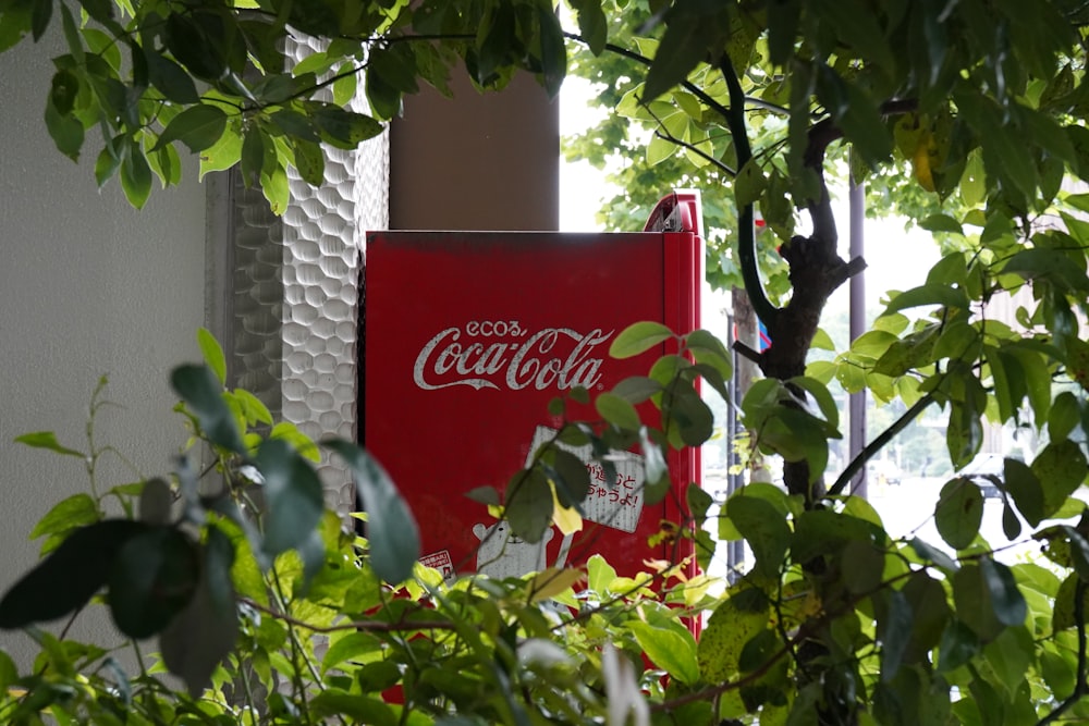 a coca - cola machine sitting in the middle of a tree