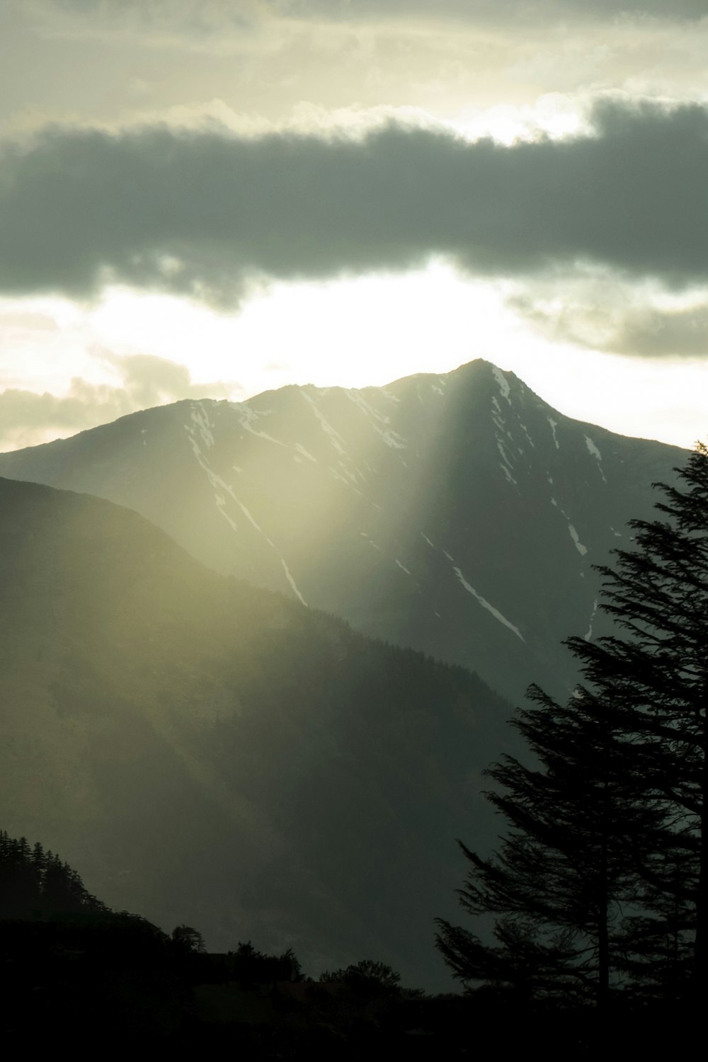 the sun is shining through the clouds over the mountains