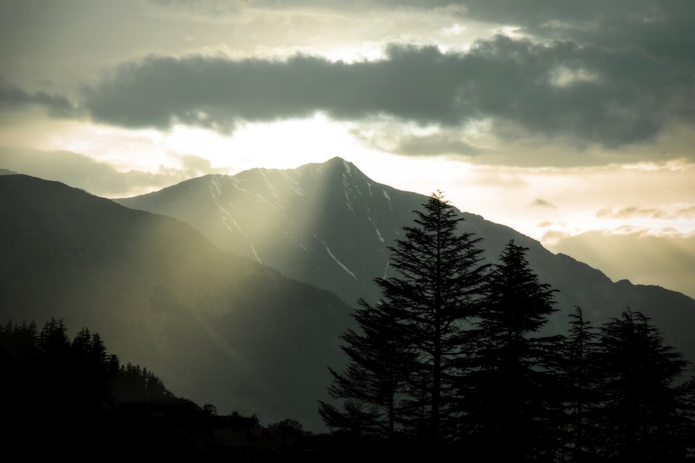 the sun is shining through the clouds over the mountains