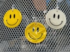 three yellow and white smiley faces hanging on a fence