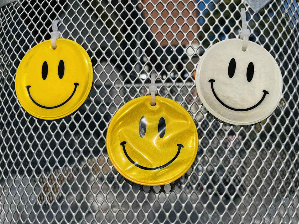 three yellow and white smiley faces hanging on a fence