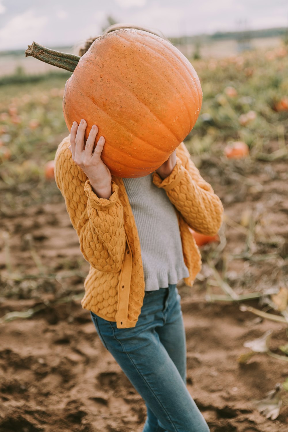a woman holding a pumpkin over her head