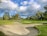 A panoramic view of a lush golf fairway beside a calm river under a clear sky.