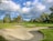 A panoramic view of a lush golf fairway beside a calm river under a clear sky.
