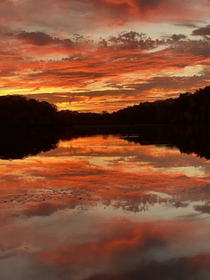 A vibrant sunset over a tranquil lake with reflections.