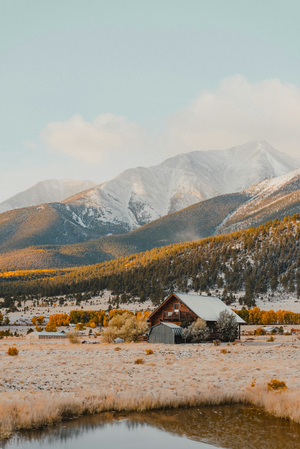 a small cabin in the middle of a field with mountains in the background