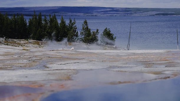 A serene morning view of Yellowstone's steaming geysers with colorful hot springs.