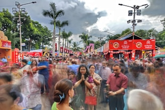 A crowded street market in Thailand bustling with locals and tourists under a cloudy sky.