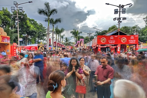 A crowded street market in Thailand bustling with locals and tourists under a cloudy sky.