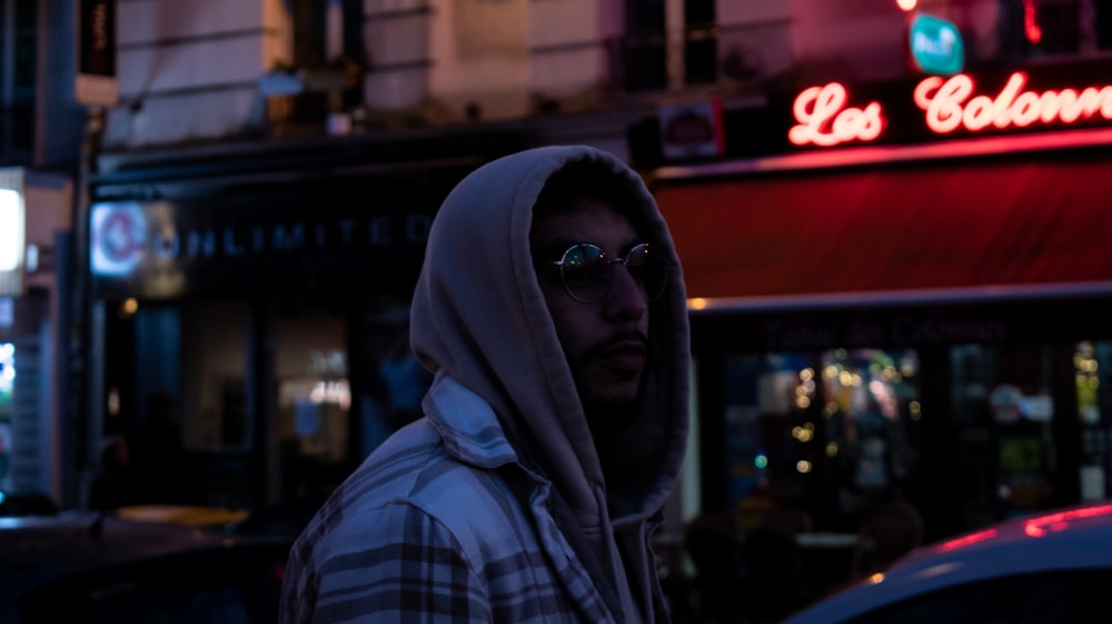 a man in a hoodie standing in front of a building