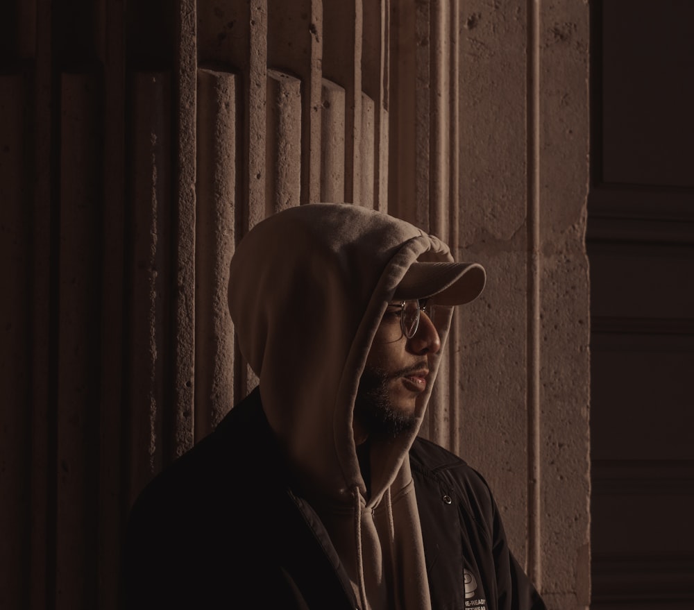 a man wearing a hoodie standing in front of a wall