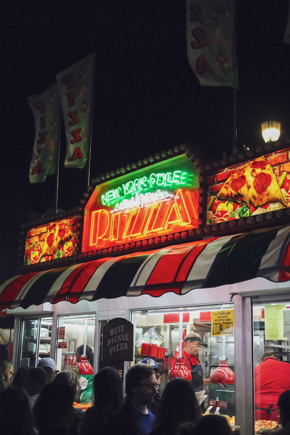 Un grupo de personas parado afuera de una pizzería