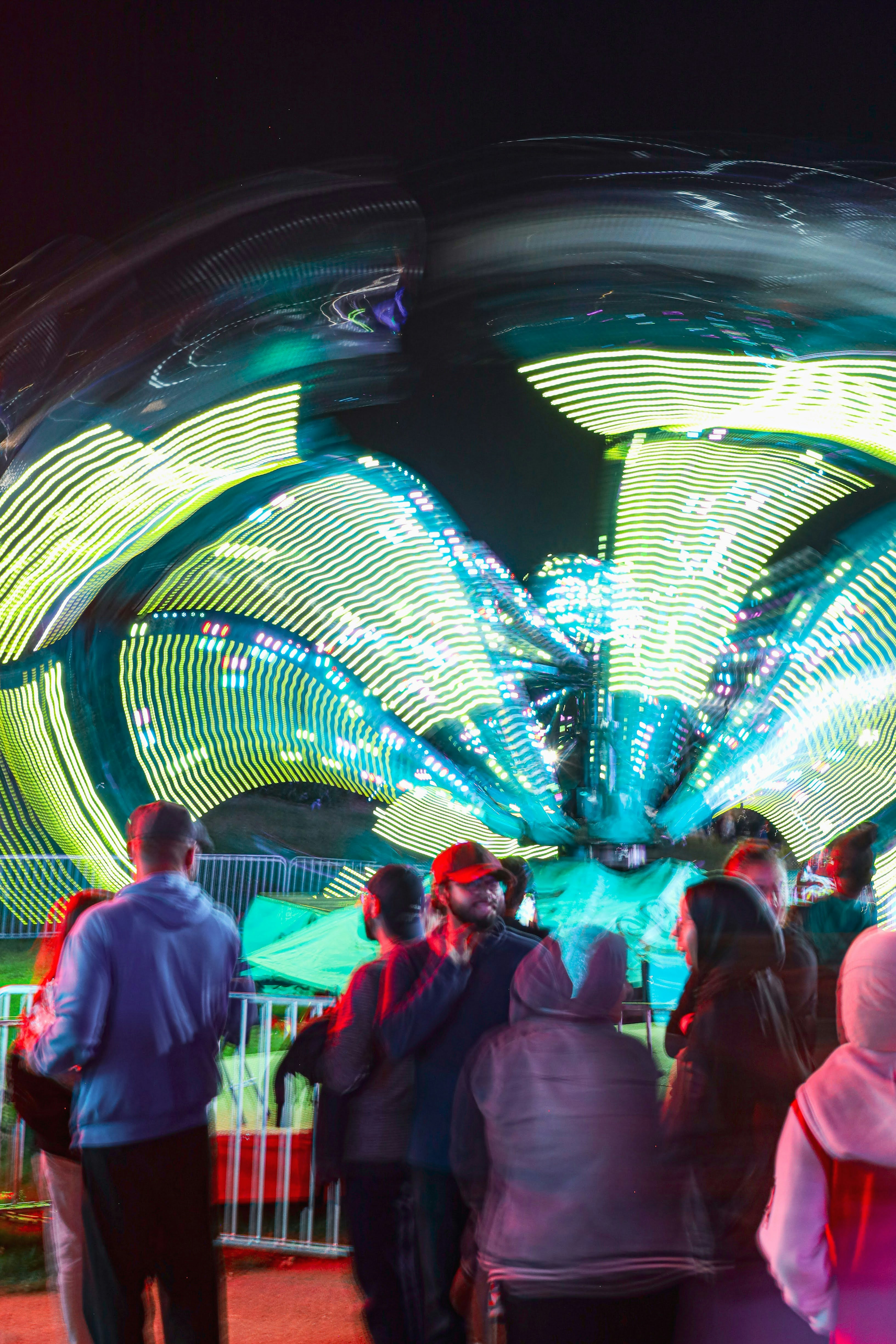 a group of people standing around a carnival ride